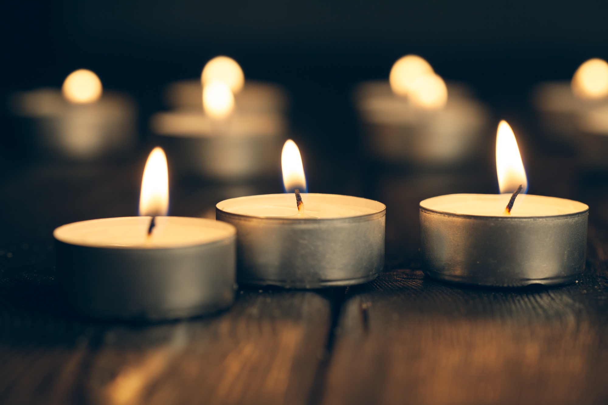 candles burning in darkness over black background. commemoration concept.