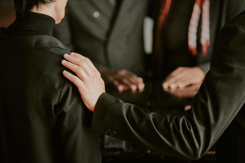 Unrecognizable Hand Comforting Woman at Funeral